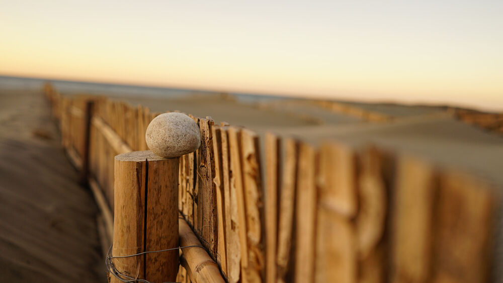 Lente Sony FE 28mm f/2 en puesto de madera con roca sobre pilar.