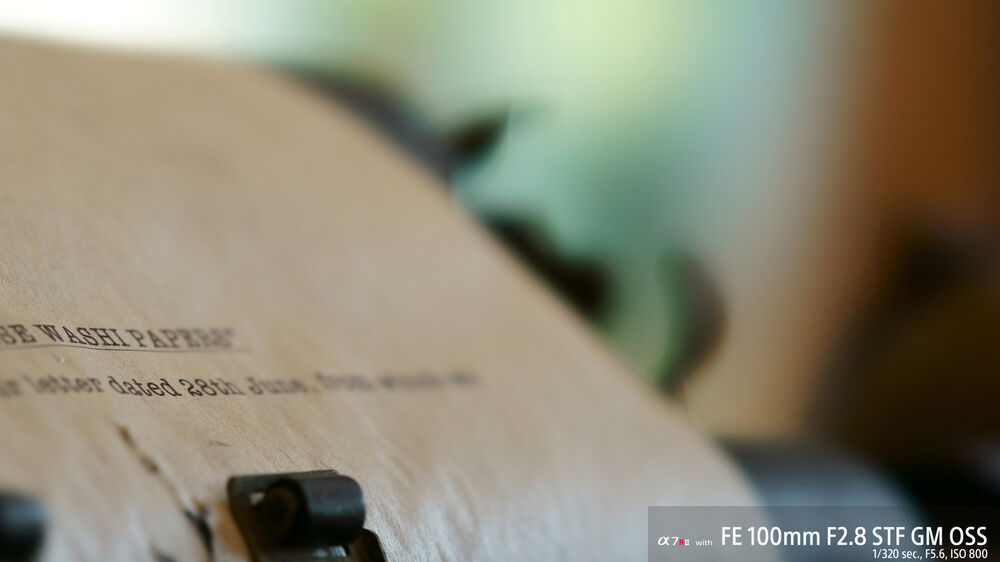 Primer plano de papel con texto, detallando una carta fechada y el lente Sony FE 100mm f/2.8 STF GM OSS.