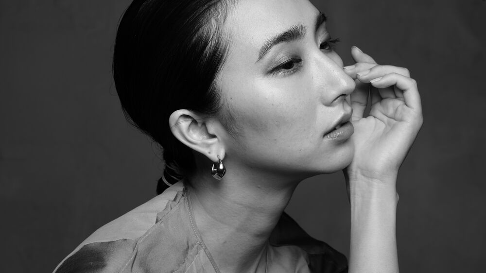 Mujer de perfil con aretes colgantes plateados y cabello recogido en coleta.