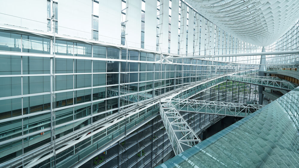 Interior moderno de arquitectura transparente y metálica, con puentes peatonales y luz natural.