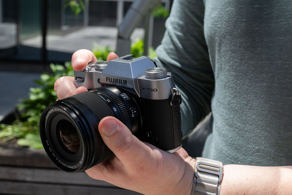 Cámara Fujifilm X-T50 plateada en mano, con lente 16-50mm, lista para usar.