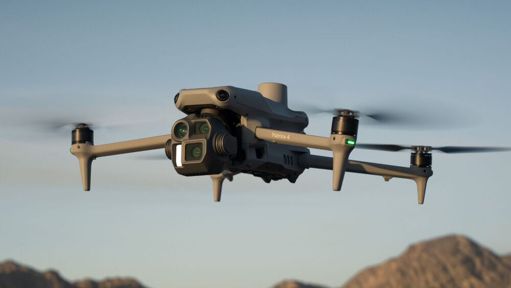 DJI Matrice 4E gris en vuelo, detallado con cámara frontal y hélices en movimiento.