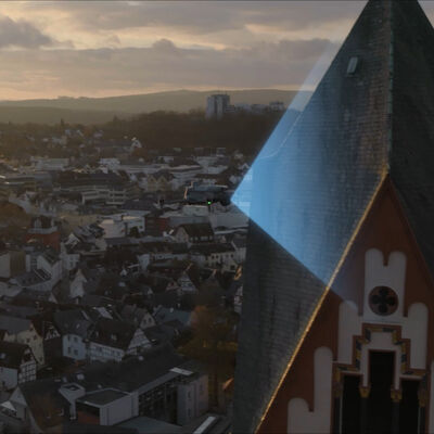 DJI Matrice 4E Drone sobrevolando una ciudad con tejados y montañas al atardecer.