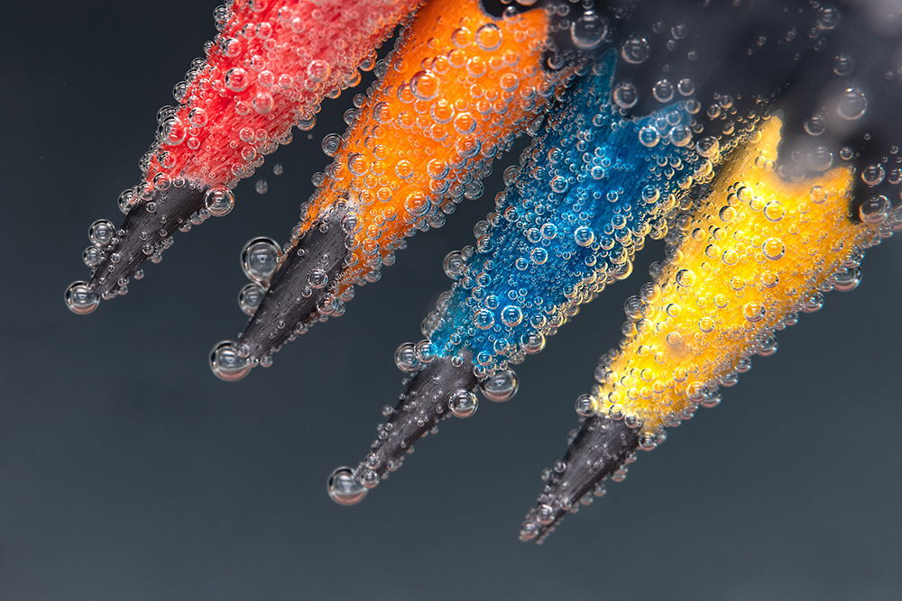 Lentes macro FUJIFILM GF 120mm f/4 en agua con burbujas, colores vibrantes: rojo, naranja, azul, amarillo.